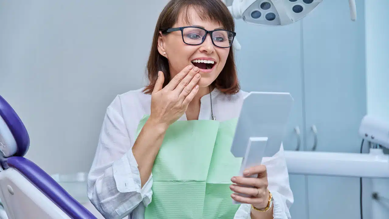Dental patient looking at dental implant in mirror